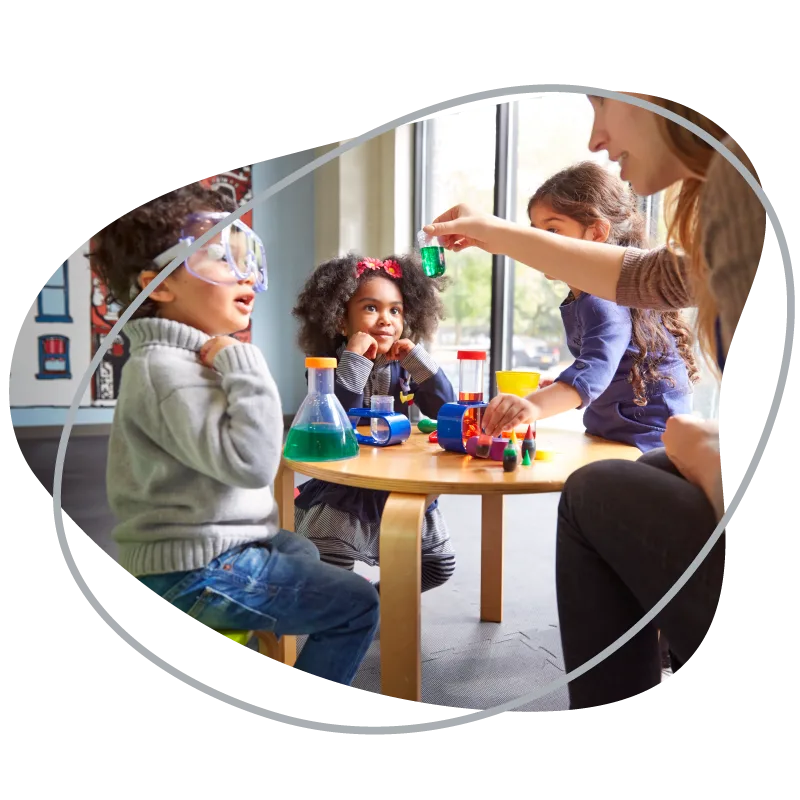 Children doing a table-top science experiment with their teacher